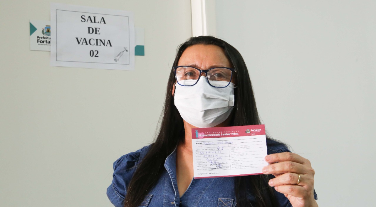 Valéria Girão Borges segura o seu cartão de vacinação
